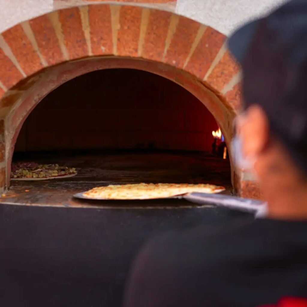 Pizzera metiendo pizza al horno